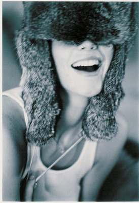 The oversized fur hat obscures identity while amplifying attitude, transforming the portrait into something rebellious, tactile, and iconic. There is tension between softness and edge, innocence and provocation.